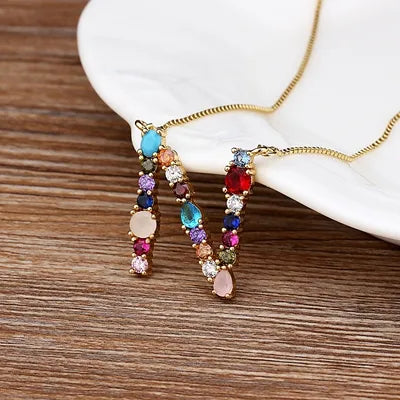 Collar con iniciales y piedras preciosas doradas de 18 quilates