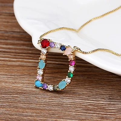 Collar con iniciales y piedras preciosas doradas de 18 quilates